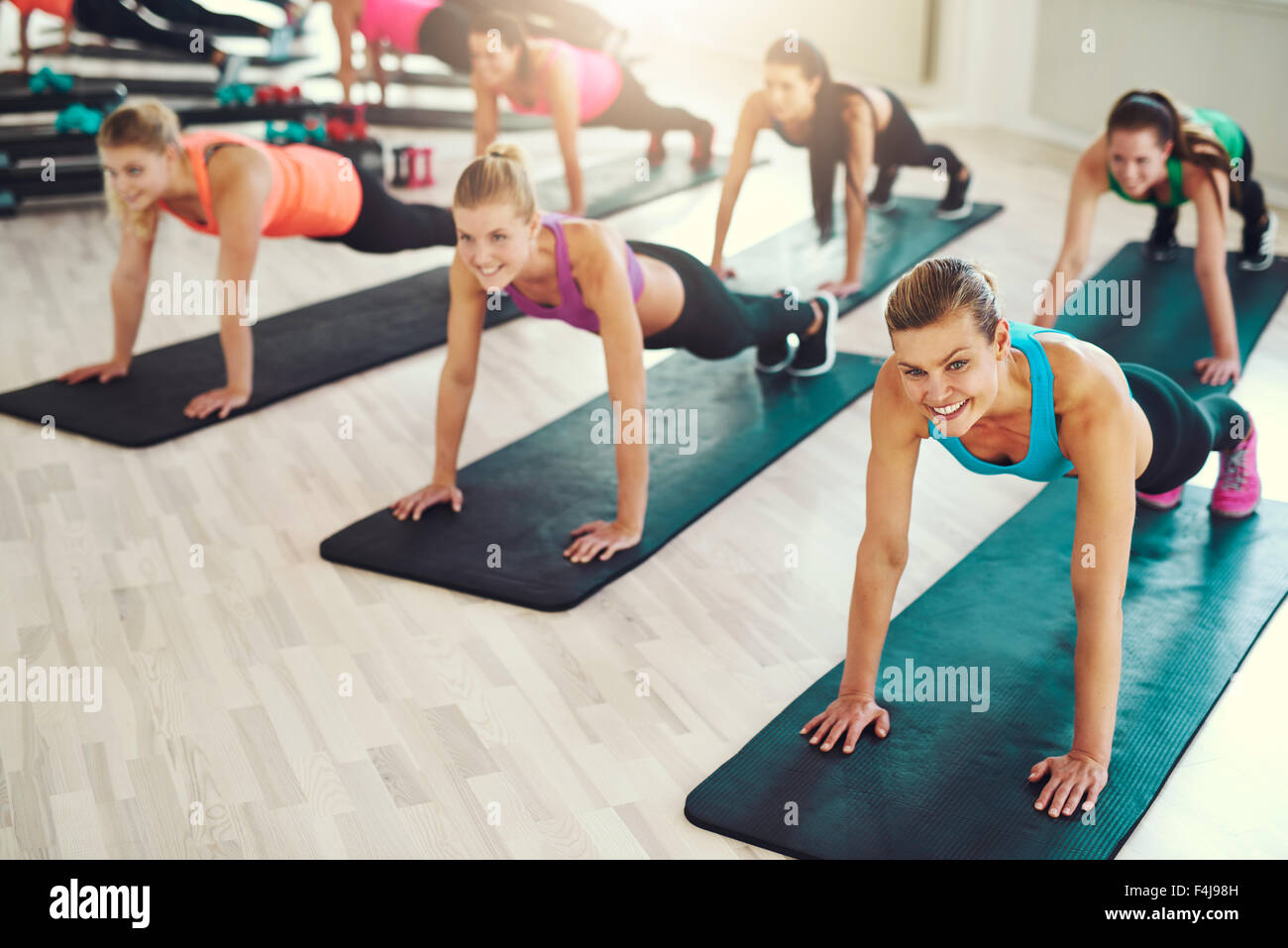 Un folto gruppo di giovani donne che lavorano in una palestra facendo spingere ups in una lezione di aerobica in una salute e concetto di fitness Foto Stock