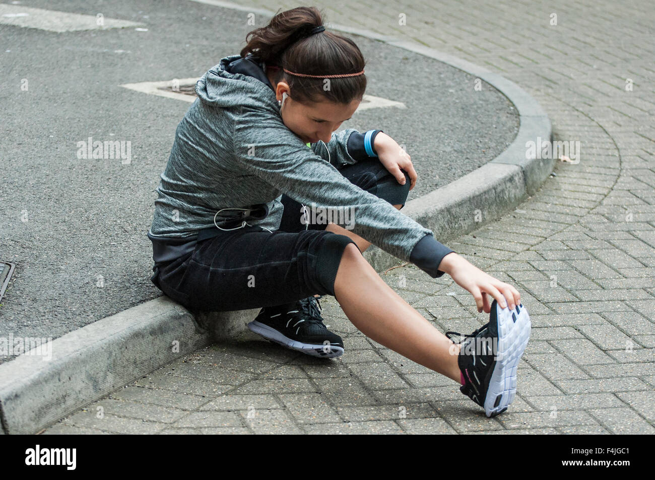 Una giovane donna fare sport e stretching outdoor con abbigliamento sportivo. Foto Stock