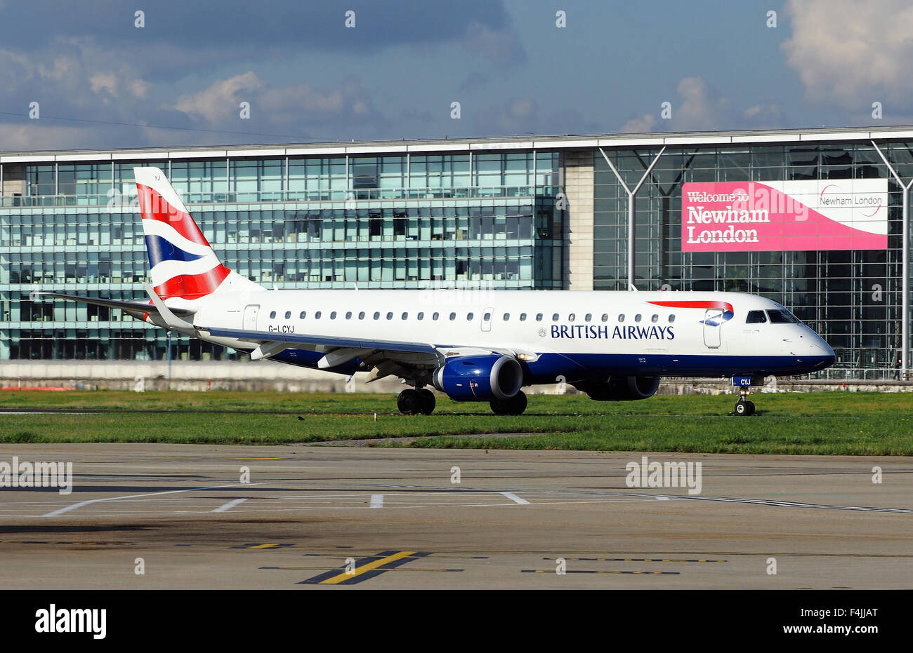 BA CityFlyer Embraer ERJ-190SR all'Aeroporto di London City con Benvenuto a Newham segno. Immagine UK DA: Geoff Moore Foto Stock