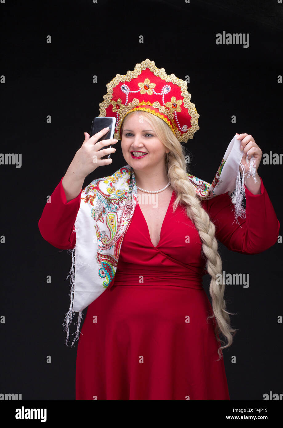 Ragazza in piedi in russo in costume tradizionale. Fare selfie. La donna indossa sarafan e kokoshnik. La ragazza in rosso il vecchio russo dre Foto Stock