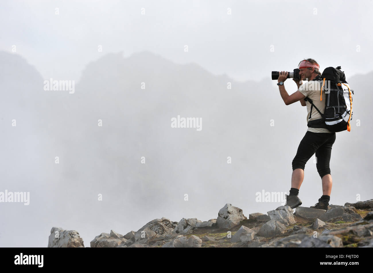 Uomo di fotografare la scena naturale dalla cima della montagna Foto Stock