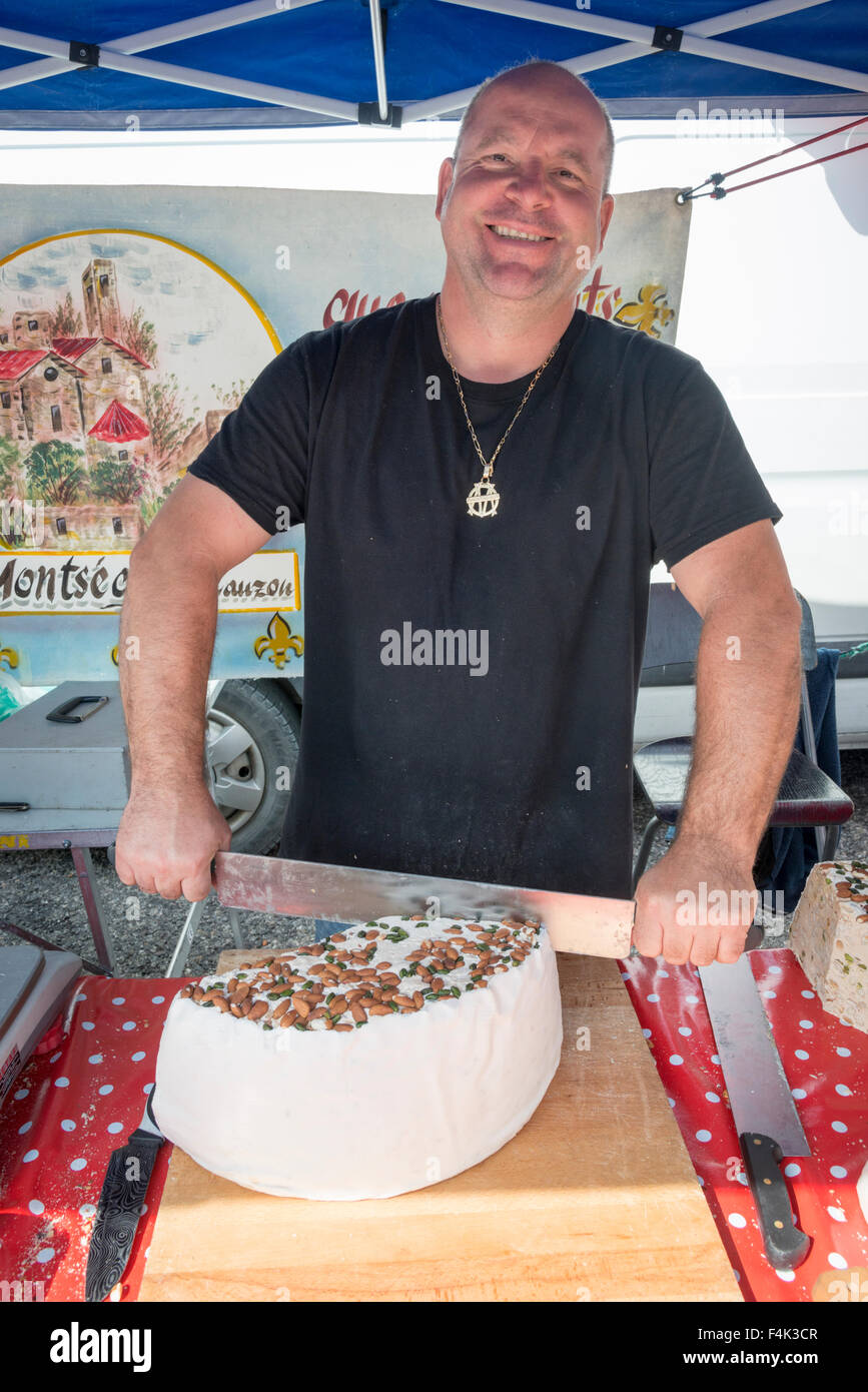 Un mercato trader tagli artigianali torrone di fatto su un mercato in stallo in Provenza Francia Foto Stock