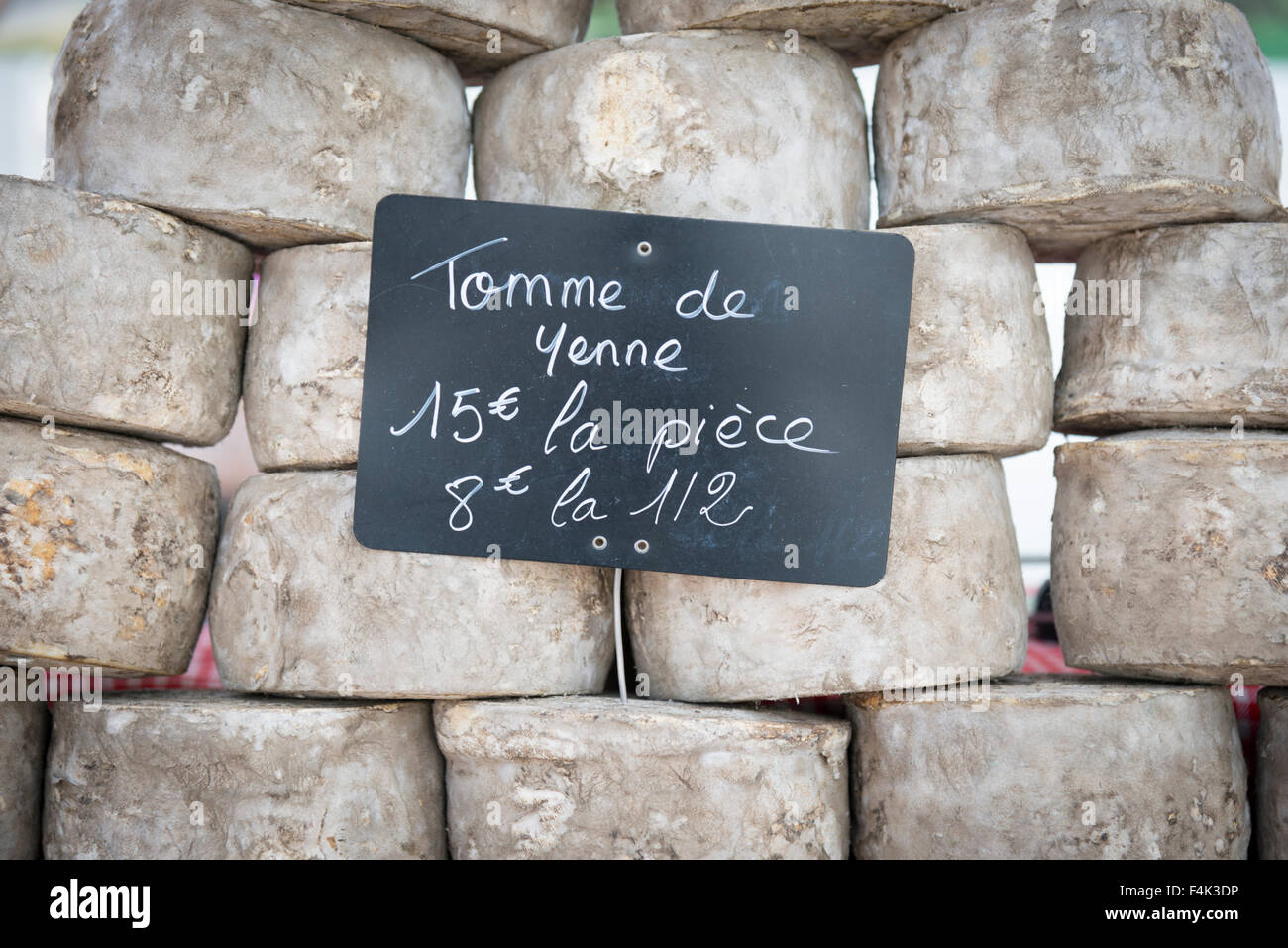 Un mucchio di Tomme de Yenne formaggio su un mercato in stallo in Francia Foto Stock