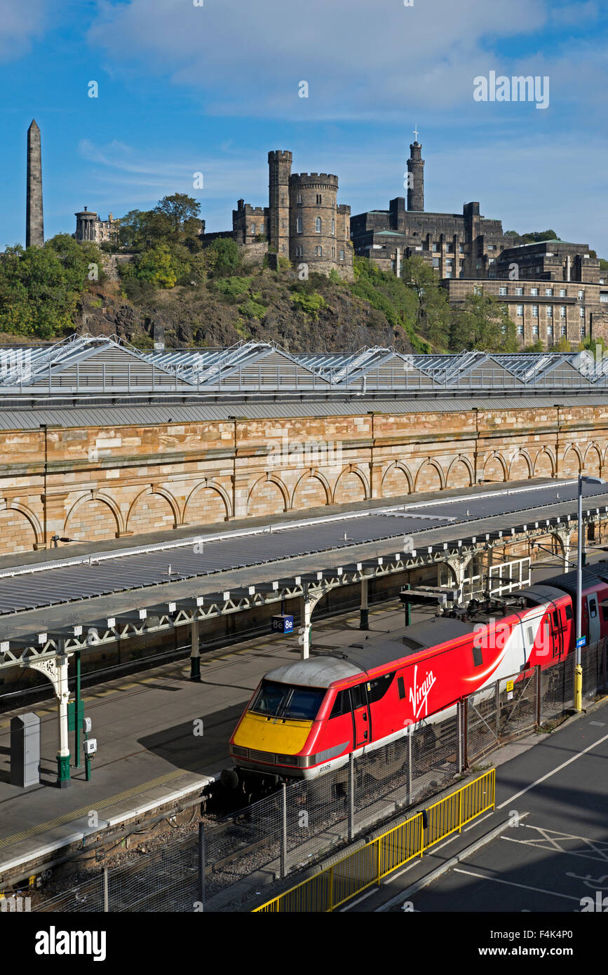 Un treno vergine permanente al Edinburgh Waverley Station con Calton Hill in background. Foto Stock