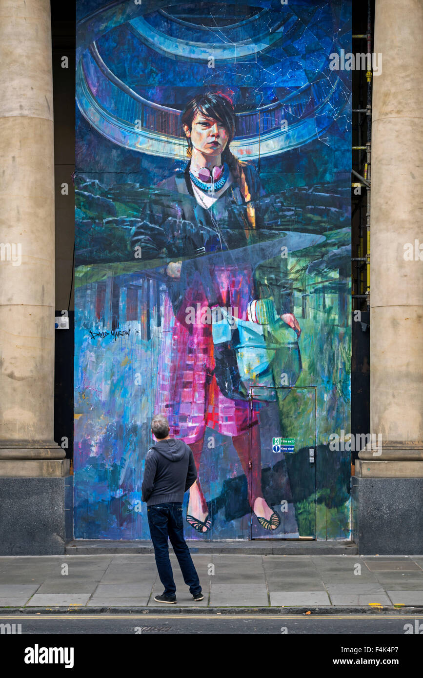 Un uomo si ferma a guardare un pezzo di arte di strada da David Martin in un edificio rinnovato in St Andrew Square, Edimburgo. Foto Stock