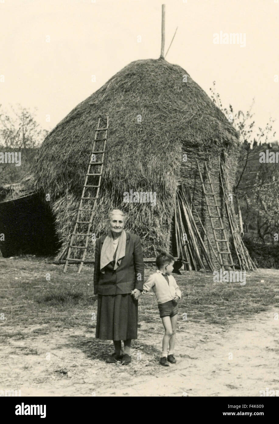 Nonna con nipote accanto a un pagliaio, Italia Foto Stock