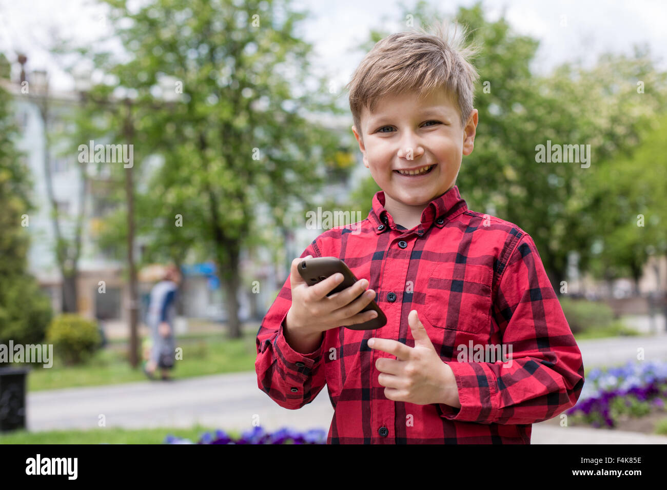 Little Boy bambino kid giochi su smartphone telefono cellulare all'aperto. Generazione di tecnologie. Foto Stock