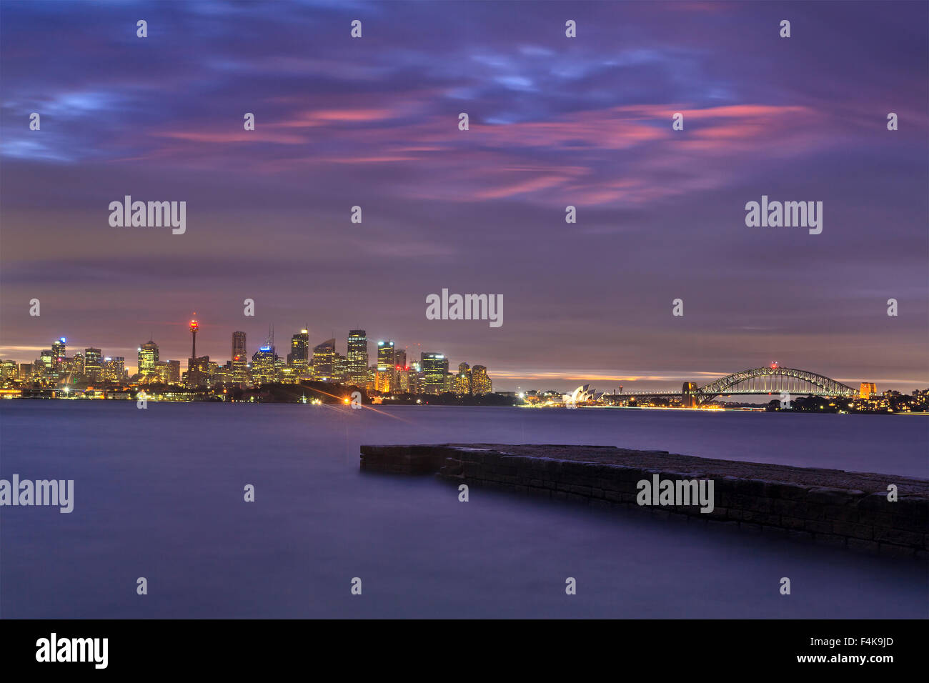 Australian delle città principali Sydney cityscape dopo il tramonto durante nuvoloso Nuvoloso meteo. CBD illuminato landmarks shot Harbour Foto Stock