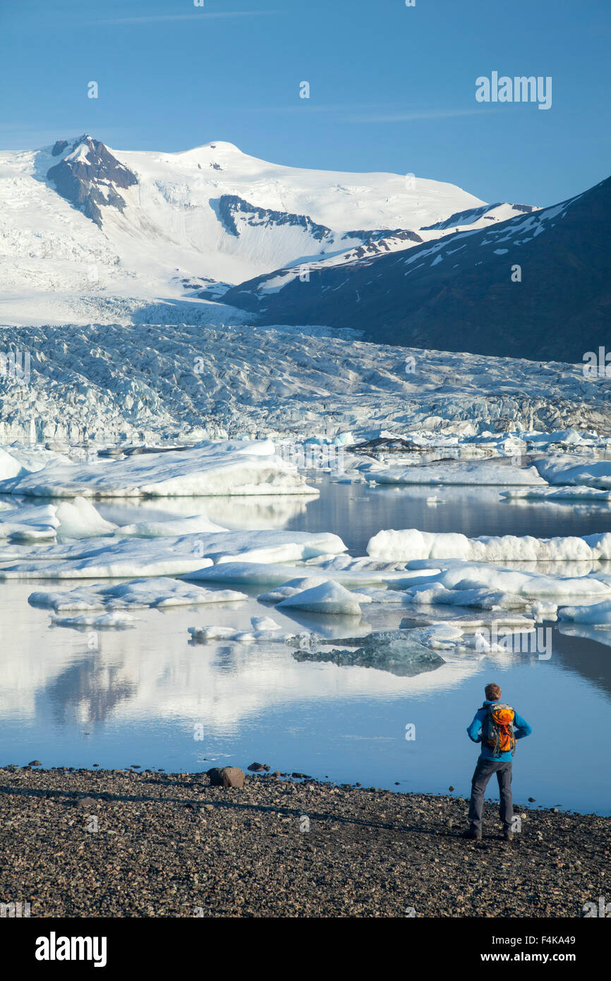 Persona accanto a Fjallsarlon laguna iceberg, al di sotto del ghiacciaio Fjallsjokull. Vatnajokull National Park, Sudhurland, Islanda. Foto Stock