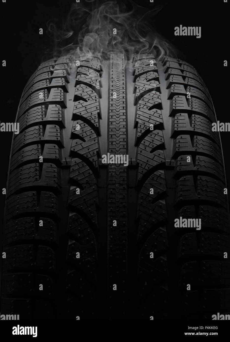 Close-up di pneumatico per automobile con fumo su sfondo nero Foto Stock