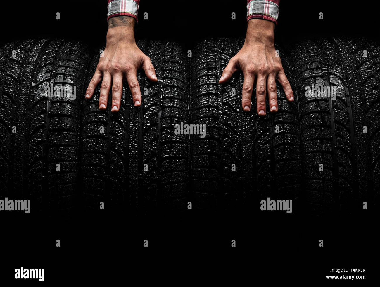 Gli uomini con le mani in mano su una vettura pneumatici, studio shot Foto Stock