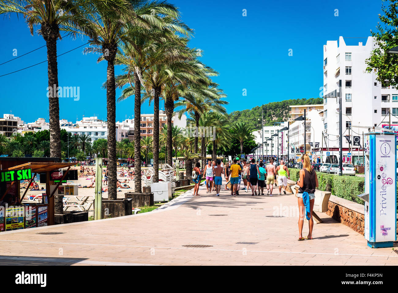 La gente camminare lungo il lungomare passeggiata costeggiata da palme in giornata soleggiata Foto Stock