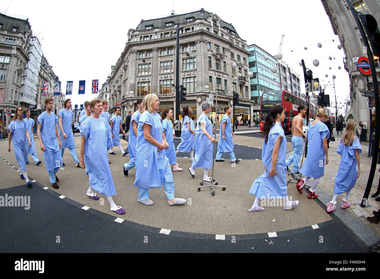 Londra, Regno Unito. Xx Ottobre 2015. Il dono della vita di donatore di organi di dimostrazione di consapevolezza a Oxford Circus, Londra. Londra pendolari hanno dato una pausa per pensare come 'pazienti' cercando un donatore di organi colpiti la rush hour a Oxford Circus. Il 21 persone vestite di camici chirurgici rappresentano il numero di persone ogni settimana (3 ogni giorno) che muoiono in bisogno di un trapianto. Credito: Paul Brown/Alamy Live News Foto Stock