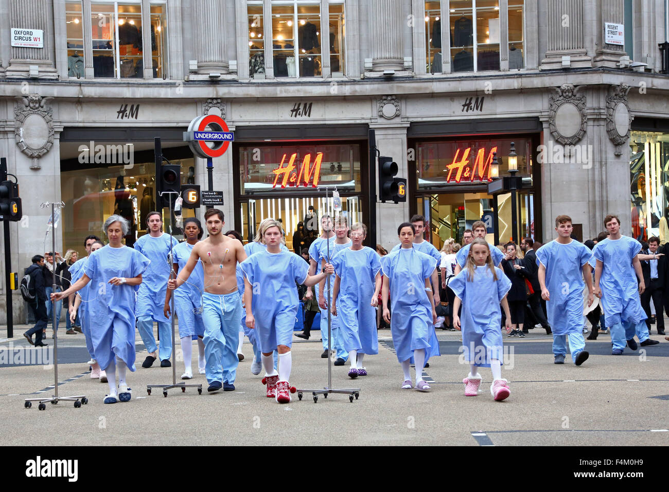 Londra, Regno Unito. Xx Ottobre 2015. Il dono della vita di donatore di organi di dimostrazione di consapevolezza a Oxford Circus, Londra. Londra pendolari hanno dato una pausa per pensare come 'pazienti' cercando un donatore di organi colpiti la rush hour a Oxford Circus. Il 21 persone vestite di camici chirurgici rappresentano il numero di persone ogni settimana (3 ogni giorno) che muoiono in bisogno di un trapianto. Credito: Paul Brown/Alamy Live News Foto Stock