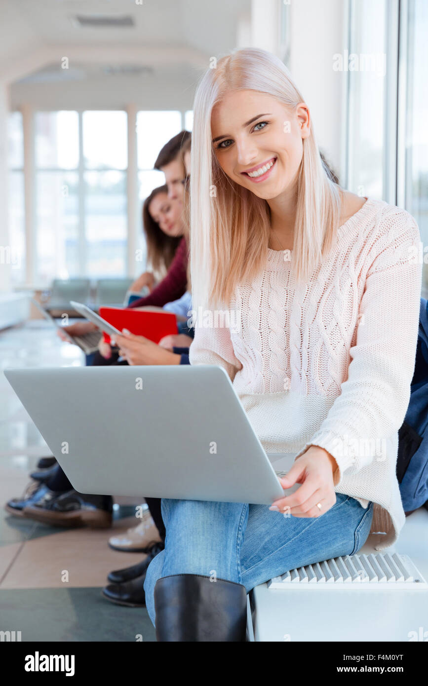 Ritratto di una donna felice studente seduto con il portatile in università hall Foto Stock