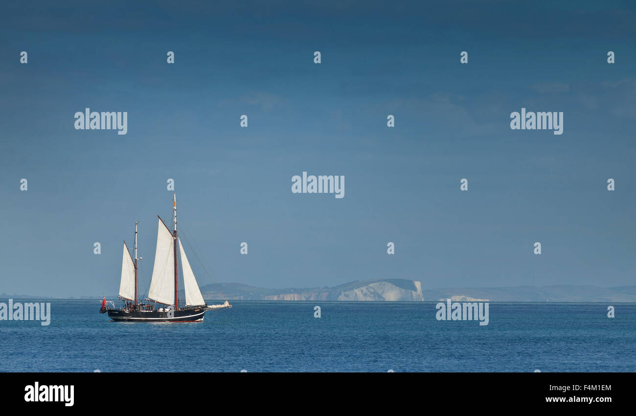 Yacht a vela nel Canale della Manica, luminosa giornata soleggiata, chalk scogliere di Poole in background Foto Stock