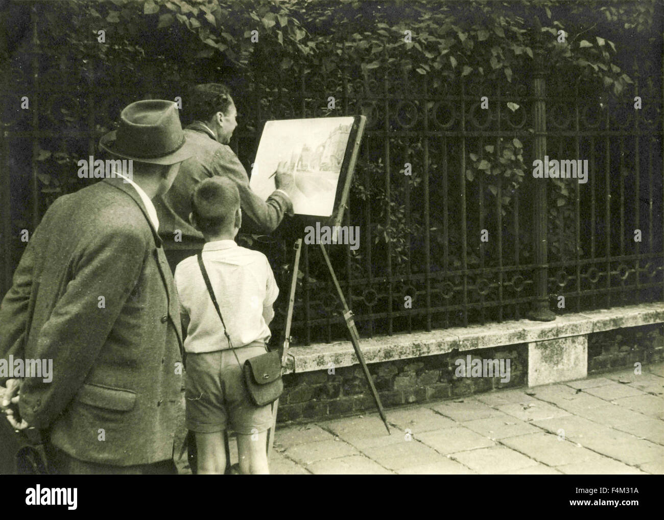 Artista dipinge in strada con curiosi dietro Foto Stock