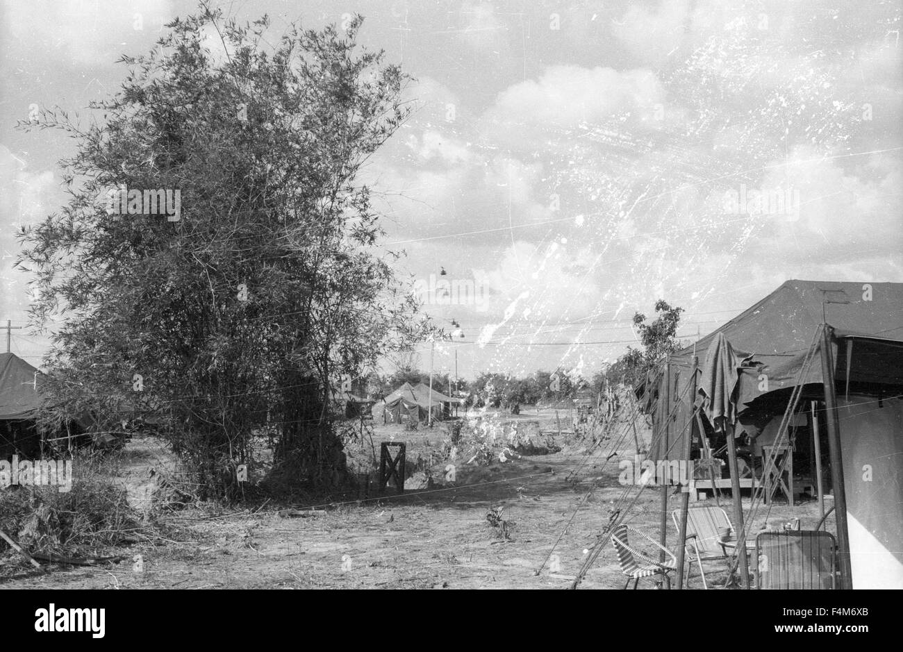 Tende a una prima divisione di fanteria base camp nel 1965 durante la Guerra del Vietnam. Huey elicotteri volare in distanza Foto Stock