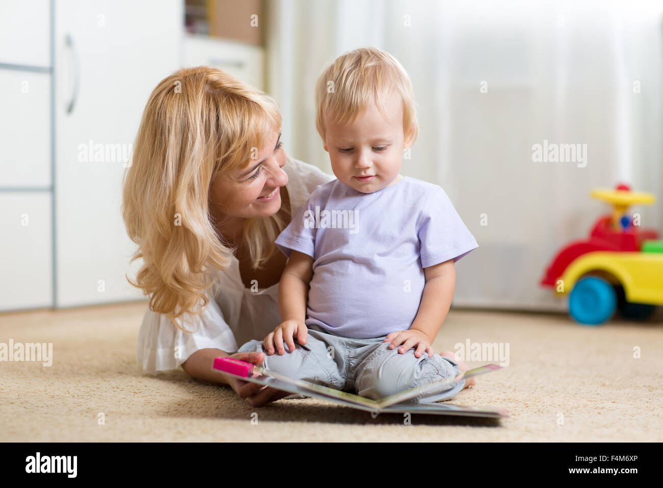 Madre felice di leggere un libro per bambini boy in ambienti interni Foto Stock