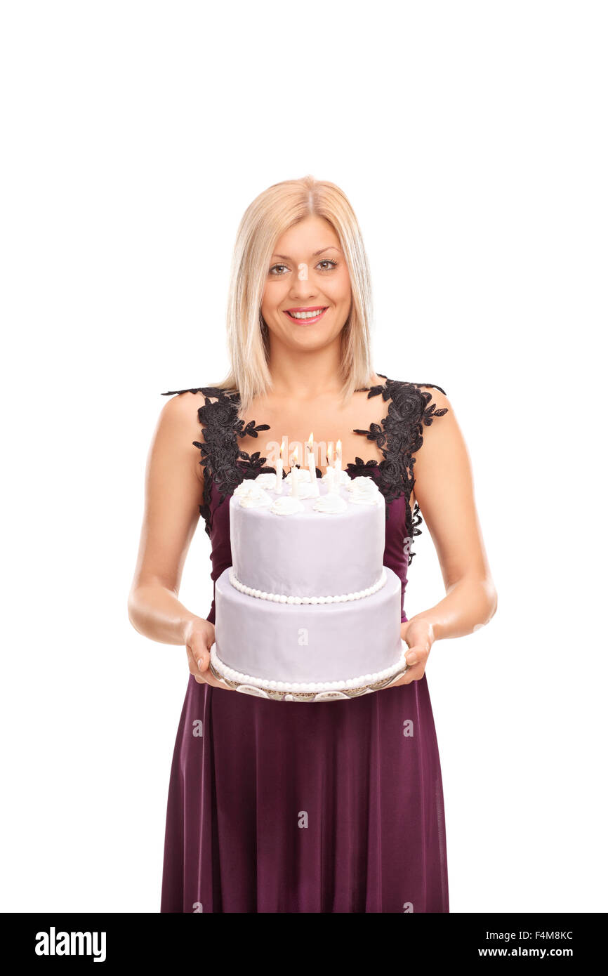 Colpo verticale di una donna elegante in un abito viola che porta una torta di compleanno con candele accese su di esso isolato su sfondo bianco Foto Stock