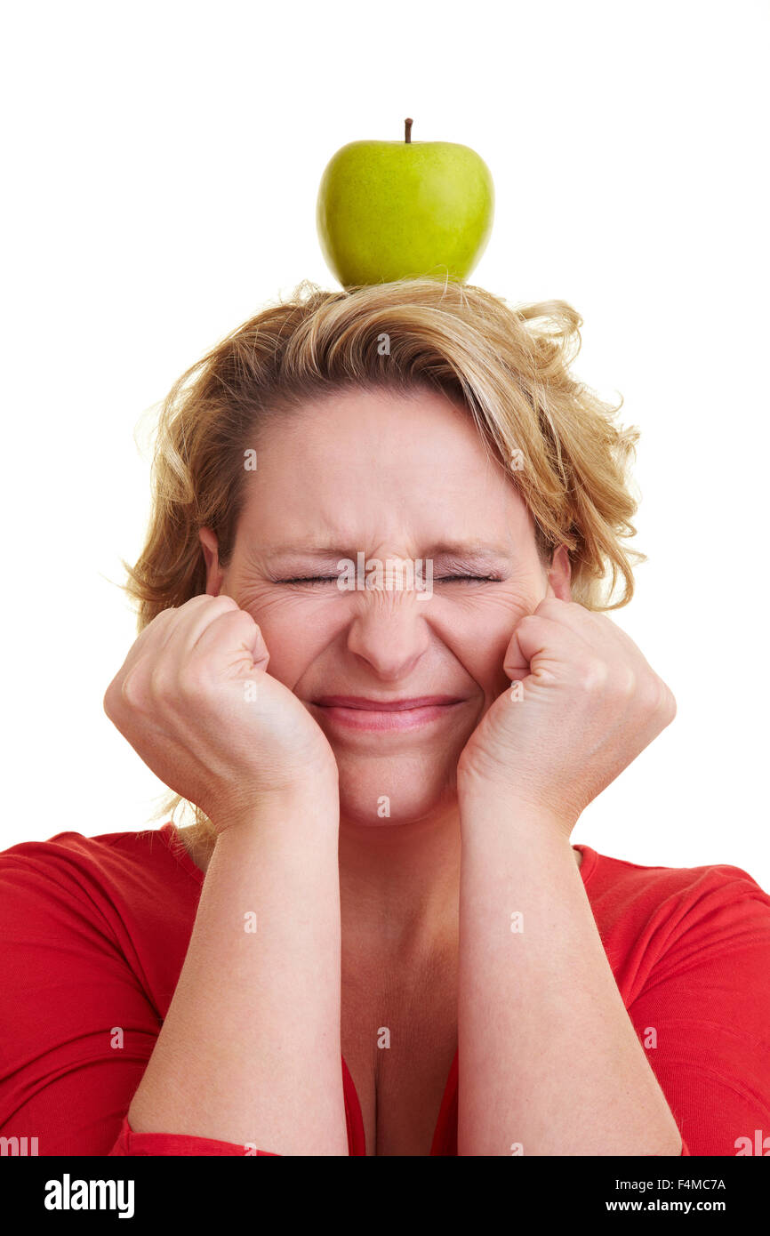 Donna bionda bilanciamento di una mela verde sul suo capo Foto Stock