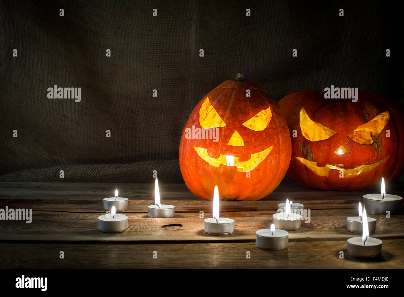 Il simbolo di Halloween zucca sorridente jack-o-lantern e candele accese sul legno scuro sfondo, orizzontale, copyspace Foto Stock Il simbolo di Halloween zucca sorridente jack-o-lantern e candele accese sul legno scuro sfondo, orizzontale, copyspace Foto Stock