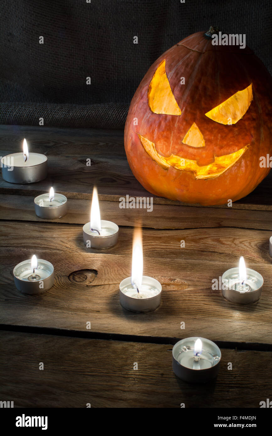 Zucca di Halloween sorridente jack-o-lantern e candele accese sul legno scuro, sfondo verticale, copyspace Foto Stock Zucca di Halloween sorridente jack-o-lantern e candele accese sul legno scuro, sfondo verticale, copyspace Foto Stock