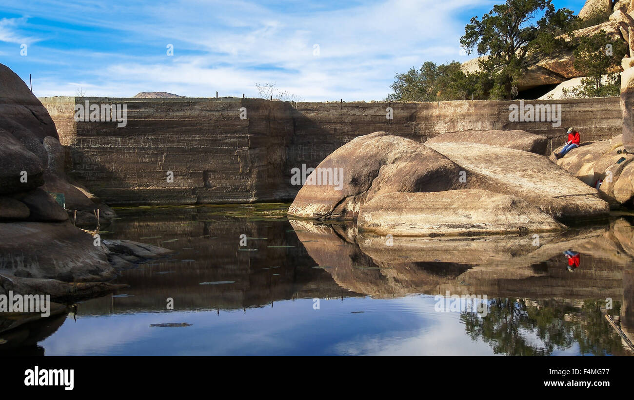 Donna seduta sulle rocce a Barker Dam a Joshua Tree National Park Foto Stock