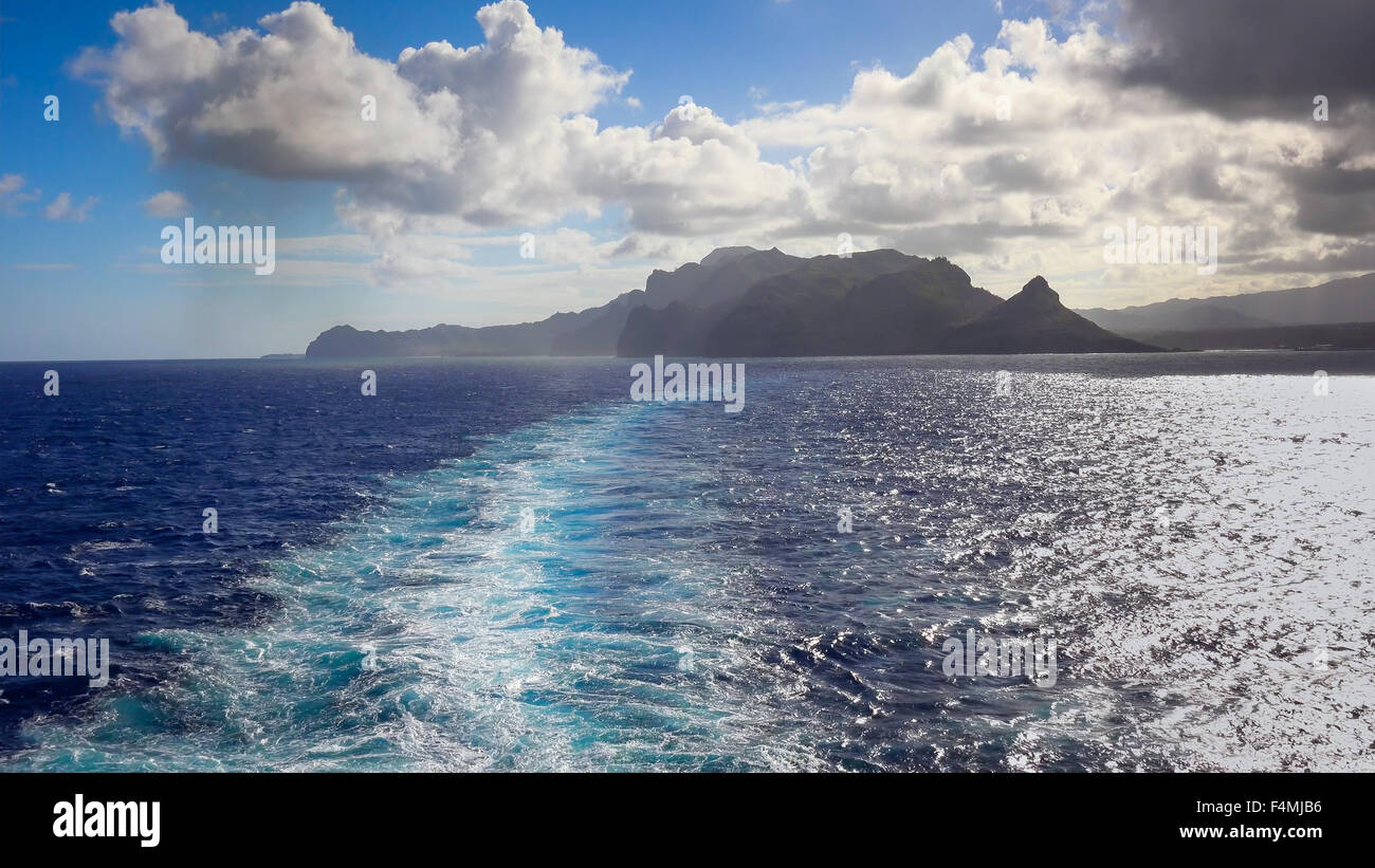 Una nave da crociera lascia una scia quando si allontana l'isola hawaiana di Kauai Foto Stock