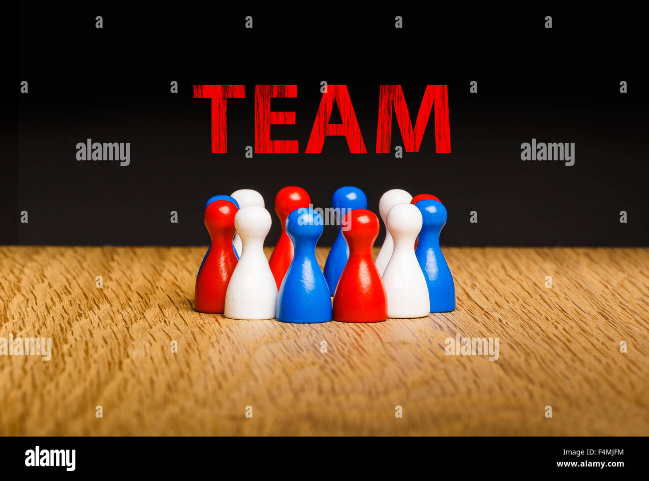 Concetto di squadra, il lavoro di squadra con gesso rosso testo. Rosso Bianco pedina blu figure e sfondo nero su legno di quercia. Foto Stock