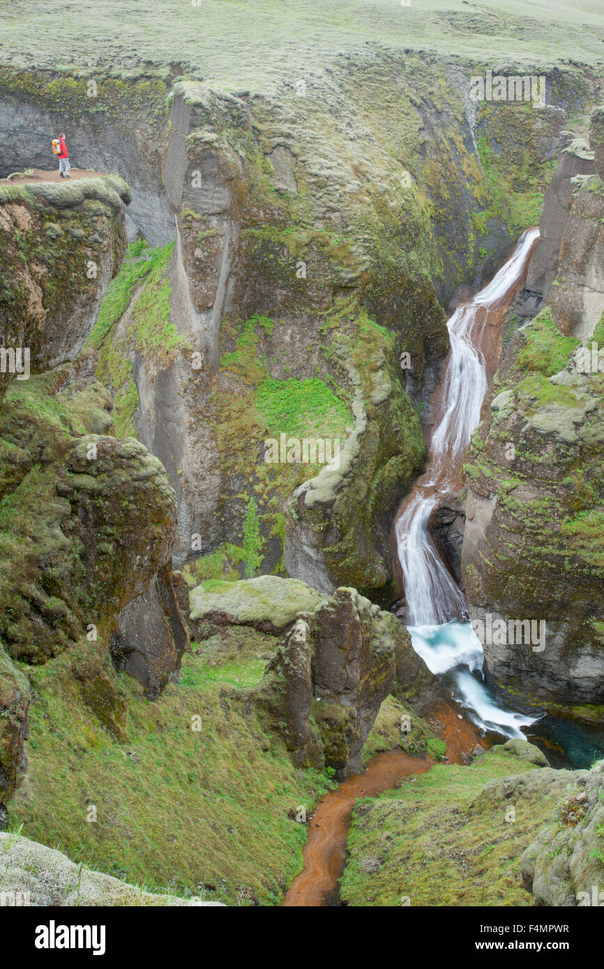 Persona sopraffatte da una cascata nel Canyon Fjadrargljufur, Sudhurland, Islanda. Foto Stock