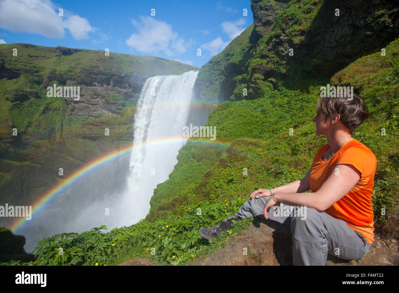 Persona ammirando 60m-alta cascata Skogafoss, Skogar, Sudhurland, Islanda. Foto Stock
