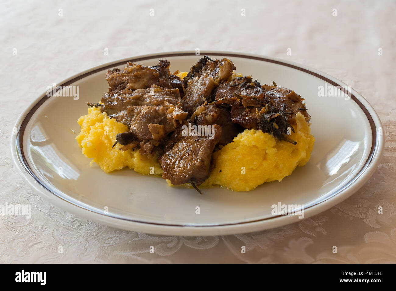 Nella foto prodotti tipici italiani ,arrosto di capra e la polenta sul piatto bianco al ristorante. Foto Stock