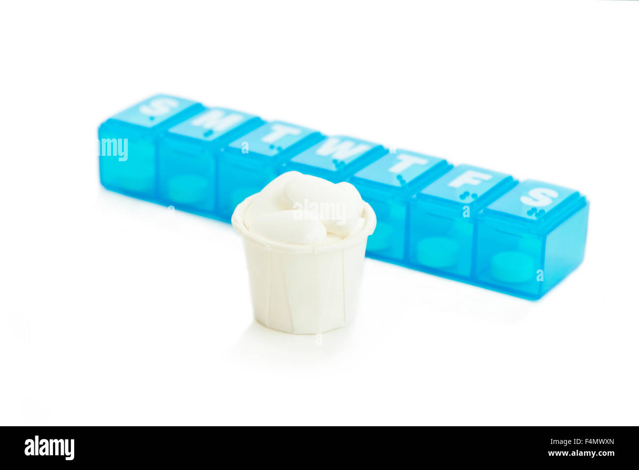 Medicina cup con assortimento di compresse bianche e quotidianamente erogatore di medicamento. Foto Stock