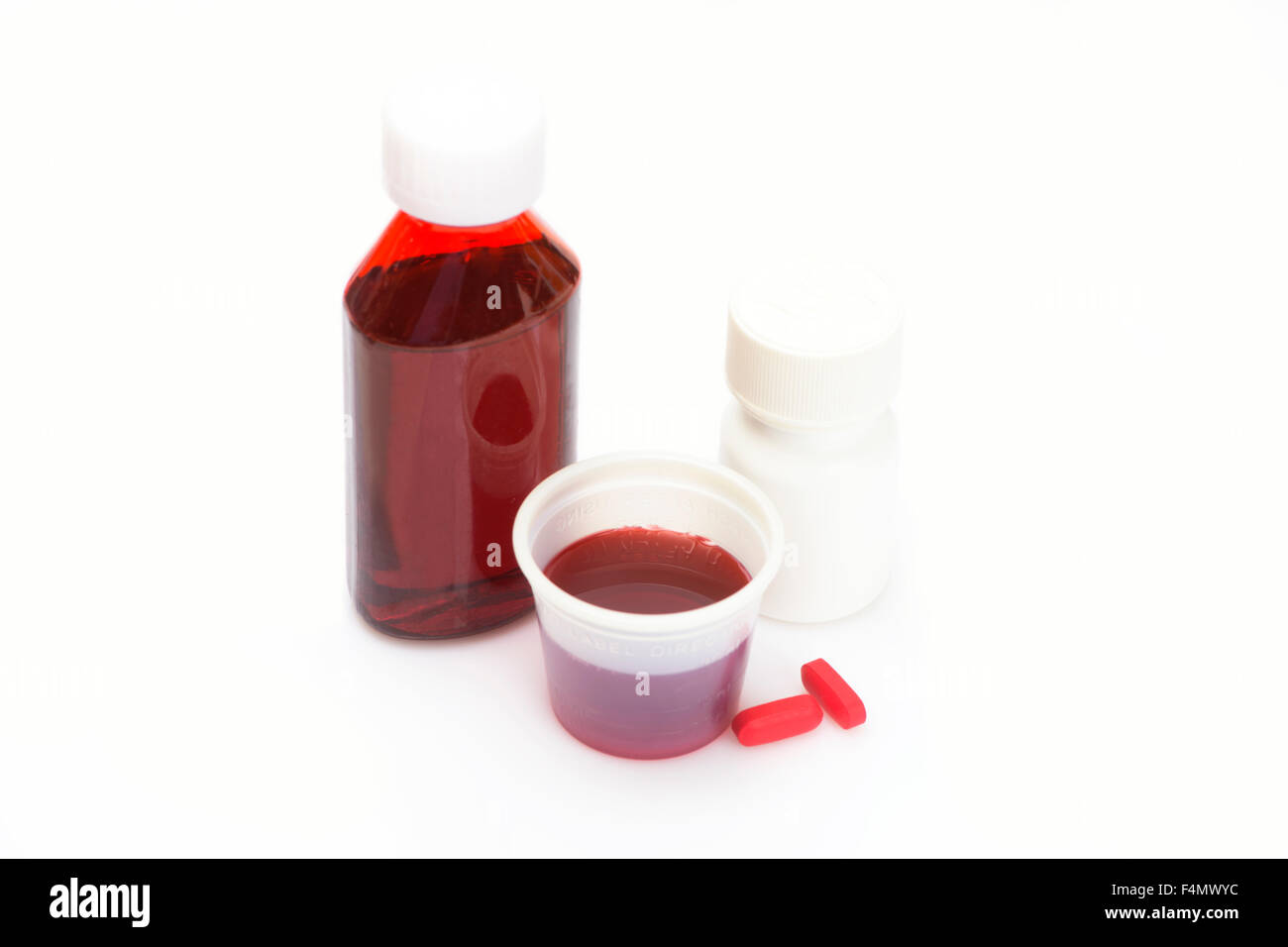 Liquido di medicina a freddo in tazza wirh flacone di farmaco e pillole di rosso. Foto Stock