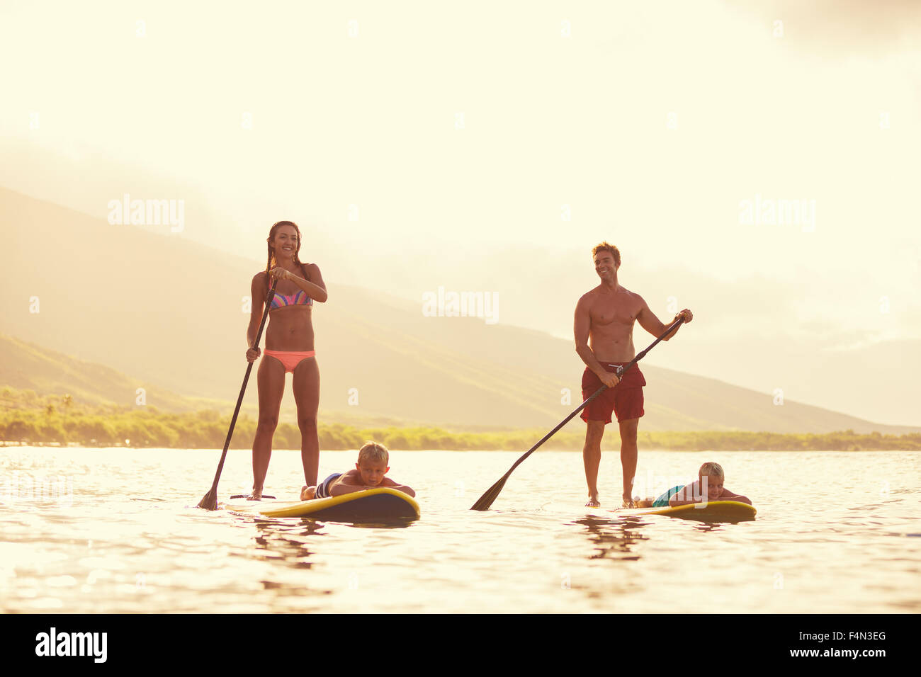 Famiglia stand up paddling presso sunrise, estate divertimento outdoor lifestyle Foto Stock