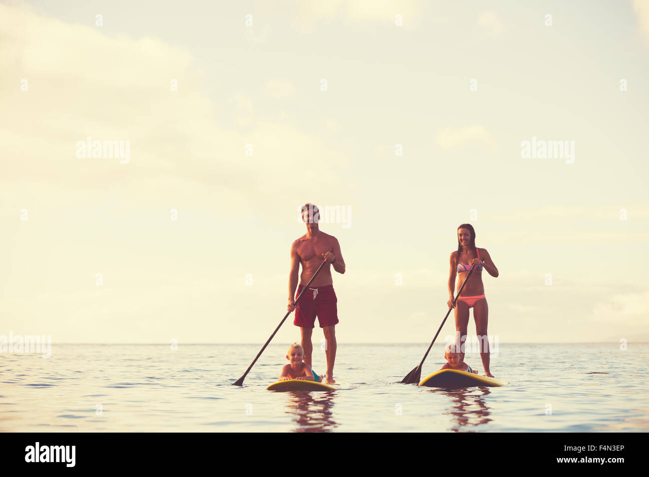 Famiglia stand up paddling presso sunrise, estate divertimento outdoor lifestyle Foto Stock