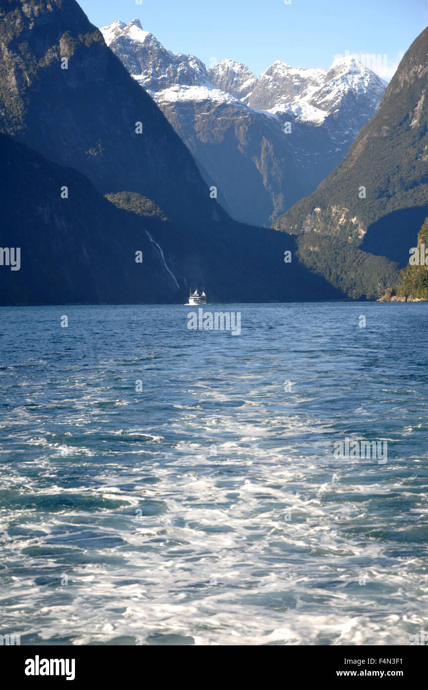 Lancio turistico sopraffatte da montagne a Milford Sound, Fiordland, Nuova Zelanda Foto Stock