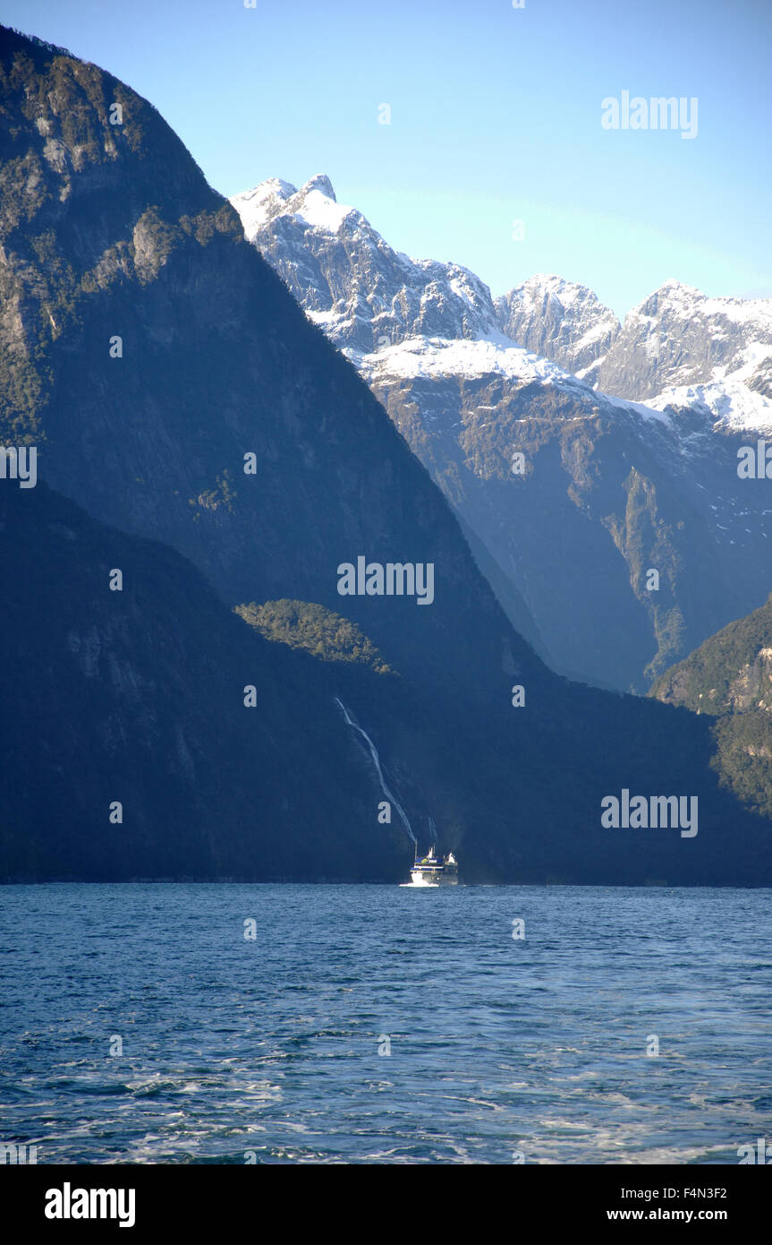 Lancio turistico sopraffatte da montagne a Milford Sound, Fiordland, Nuova Zelanda Foto Stock