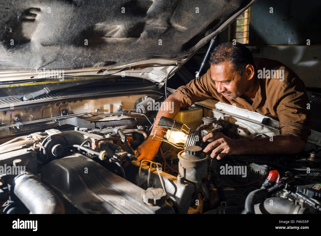 Un meccanico di automobili è la riparazione di un tedesco BMW auto in un garage convenzionato situato nel sobborgo di fort Foto Stock