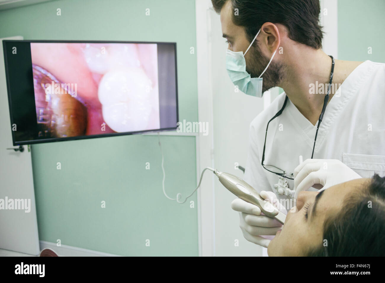 Dentista esaminando la bocca di un paziente con una telecamera intraorale Foto Stock