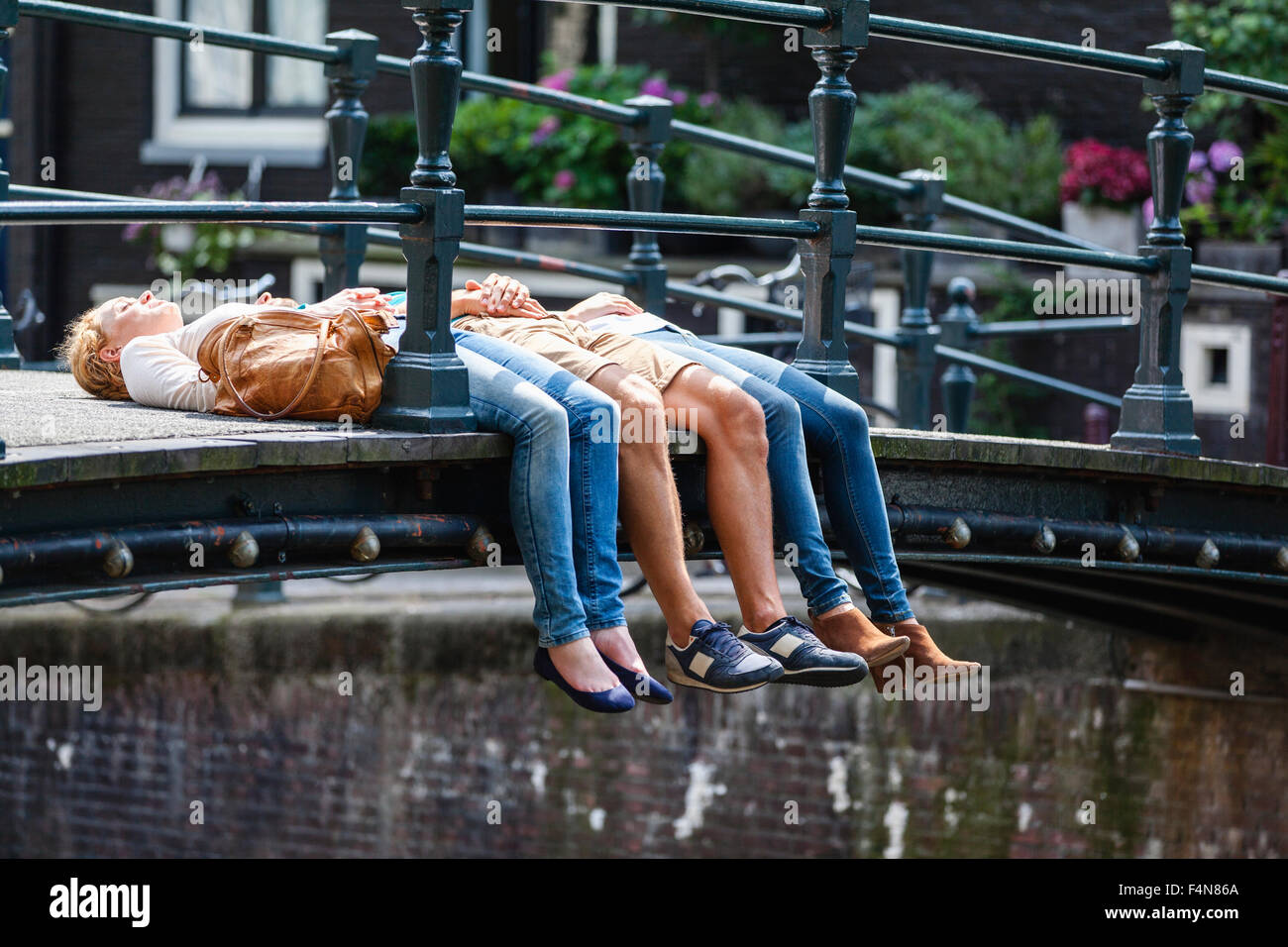 Paesi Bassi, Amsterdam, tre amici giacente sul ponte Foto Stock