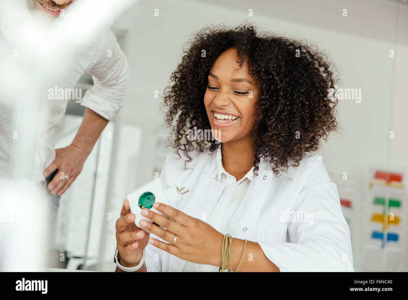 Sorridente donna scienziato azienda green presa a spina in laboratorio Foto Stock