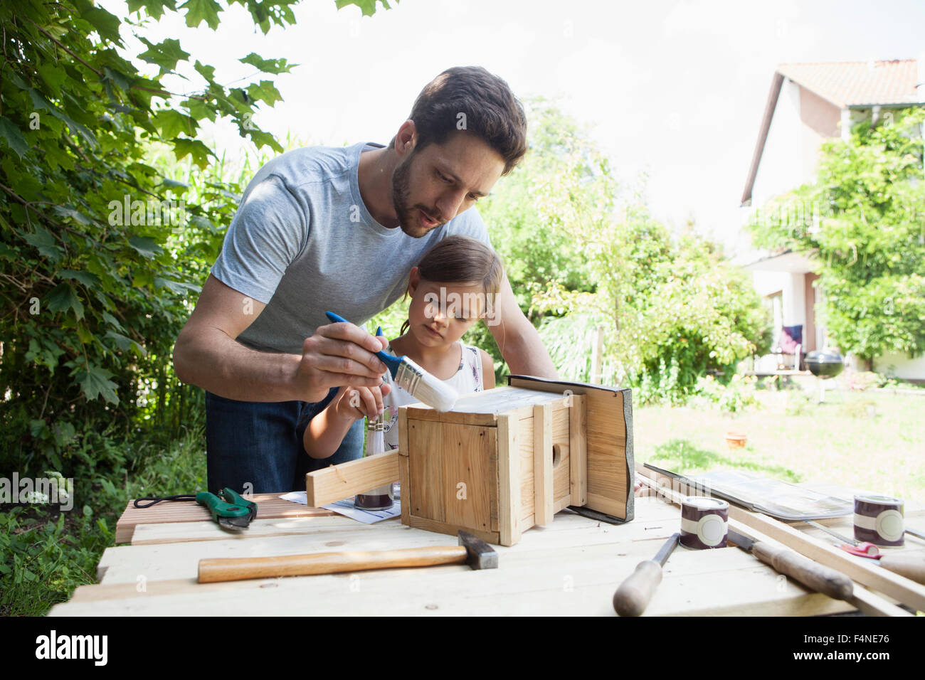 Padre e figlia di verniciatura di un birdhouse Foto Stock