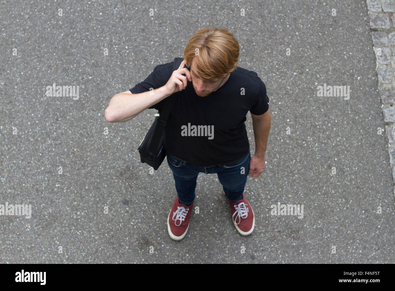 Ritratto di giovane uomo in piedi su una strada di telefonare con lo smartphone Foto Stock