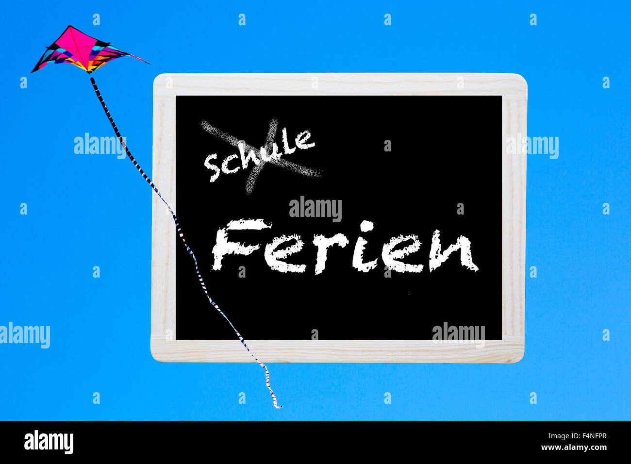 Lavagna con parole tedesche 'Schule-Ferien' (scuola-vacanza) con l'aquilone nel cielo Foto Stock