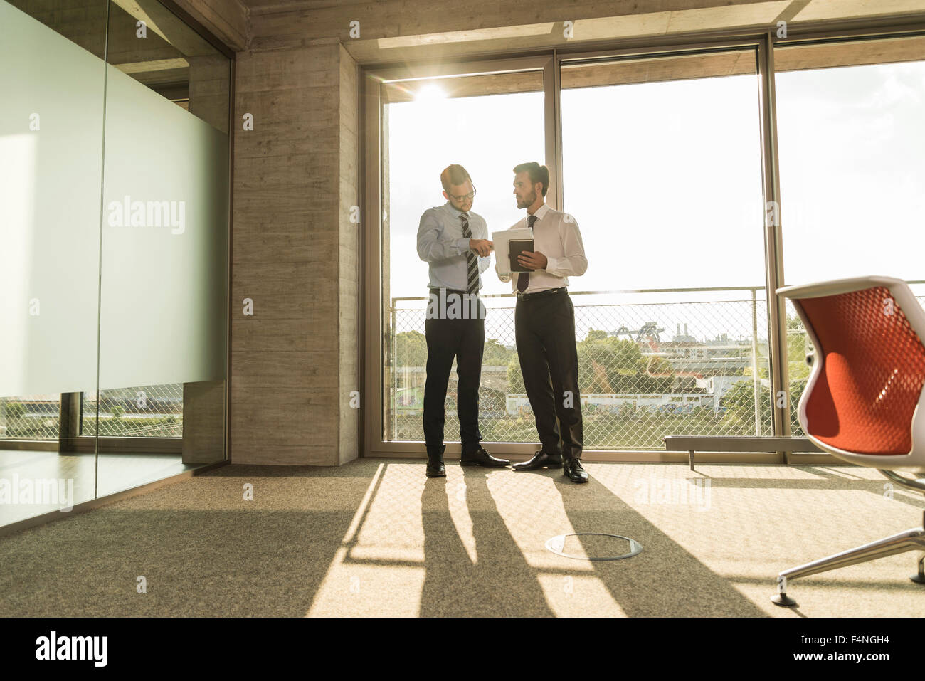 Due giovani imprenditori parlando nella finestra di office Foto Stock