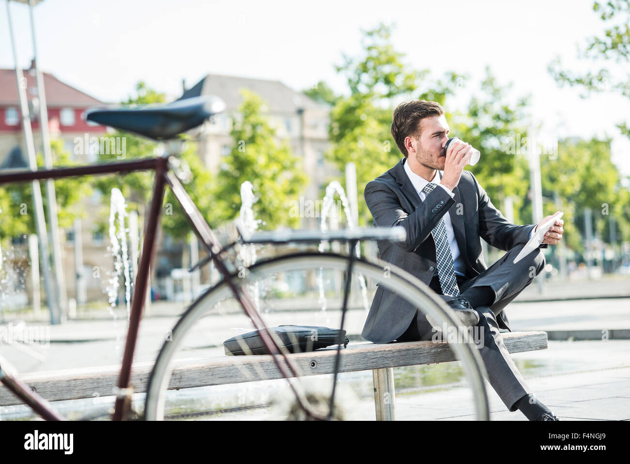 Giovane imprenditore seduta sul banco di lavoro tramite tavoletta digitale Foto Stock