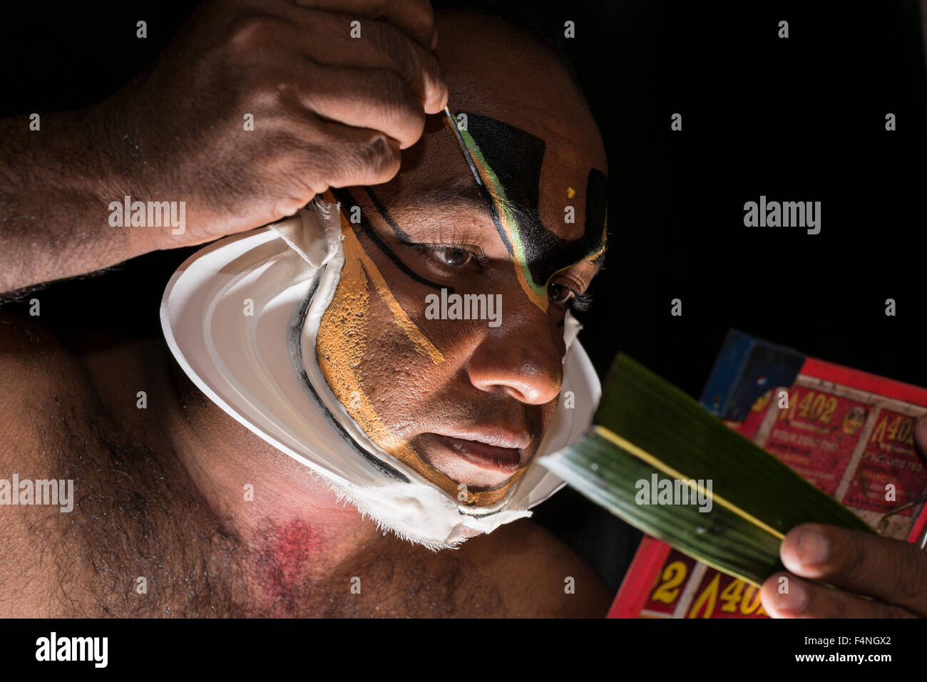 Un artista katakali è applicare il make up del carattere di Shiva per il gioco dhecheyagam Foto Stock