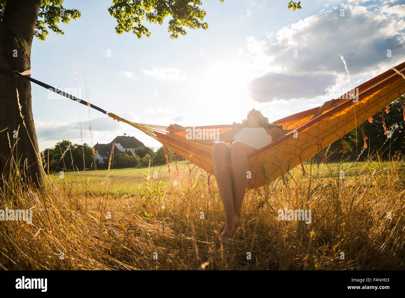 Donna con cuffie giacente in un amaca relax nella natura Foto Stock